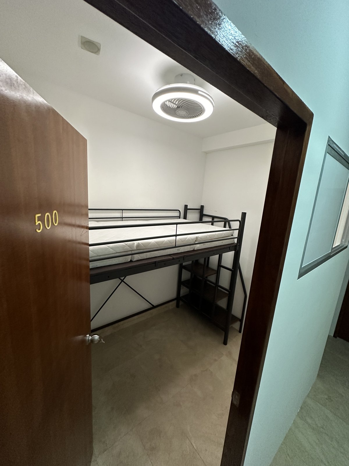 Room 500 — raised bed frame with desk beneath, ceiling fan